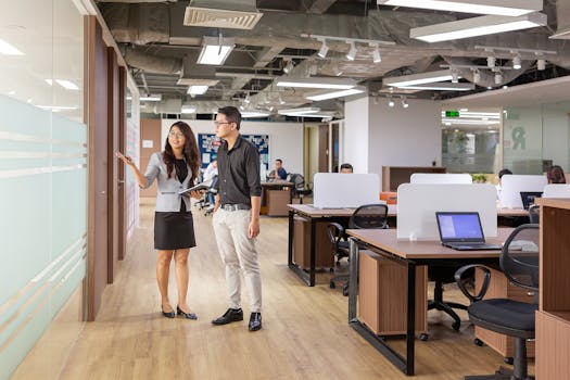 Asian professionals discussing in a contemporary office setting with open workspaces.